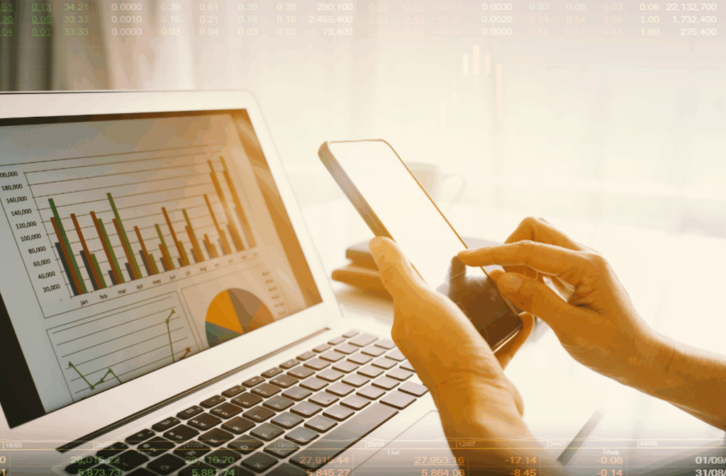 Person analysiert Finanzdiagramme auf Laptop und Smartphone gleichzeitig