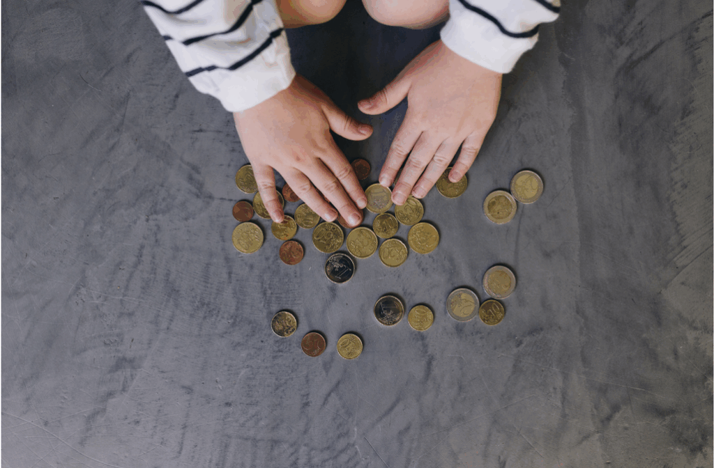 Kinderhände zählen Euromünzen auf einem grauen Untergrund