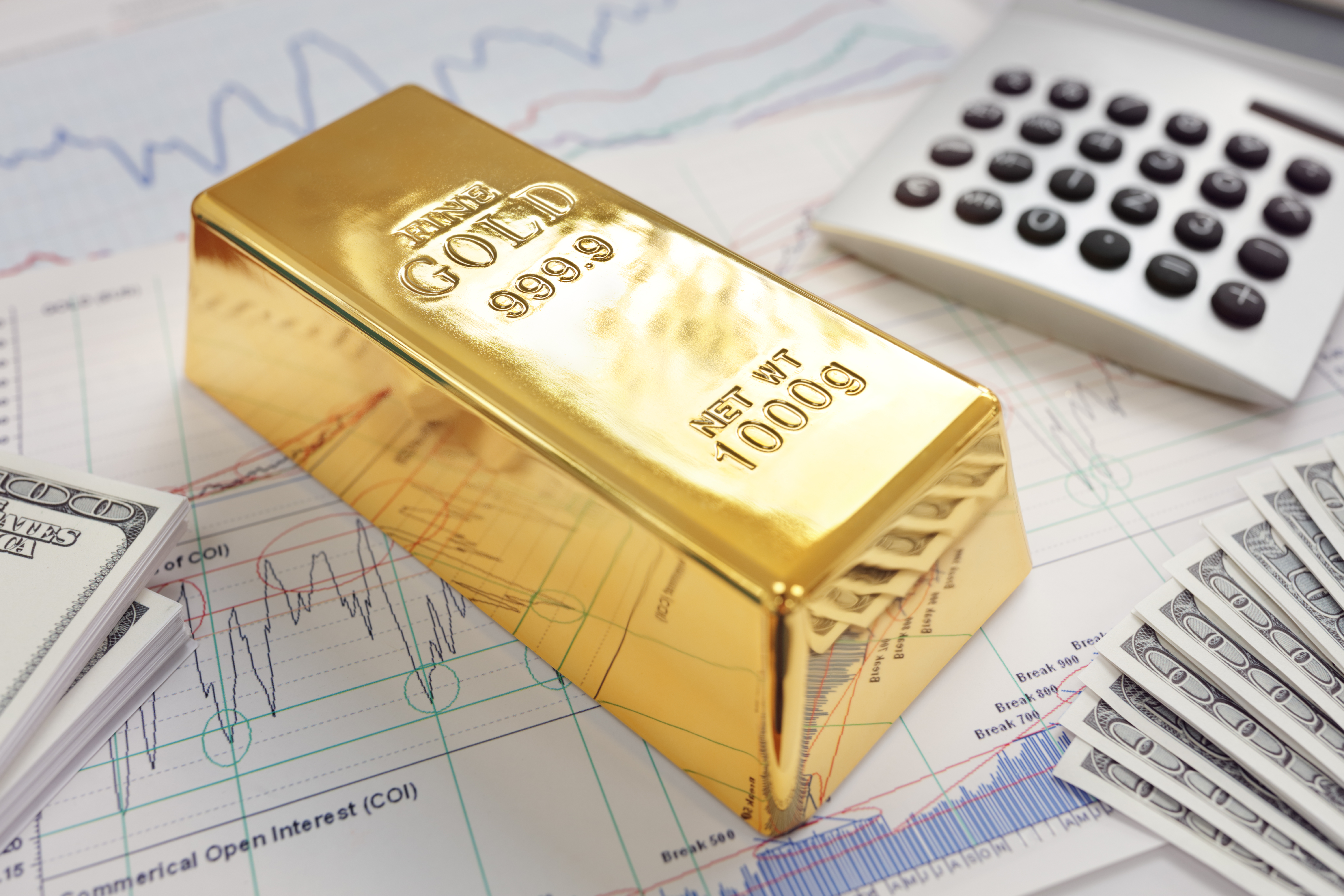 Goldbarren auf Finanzunterlagen mit Dollar-Scheinen und Taschenrechner – Symbol für Altersvorsorge mit Gold